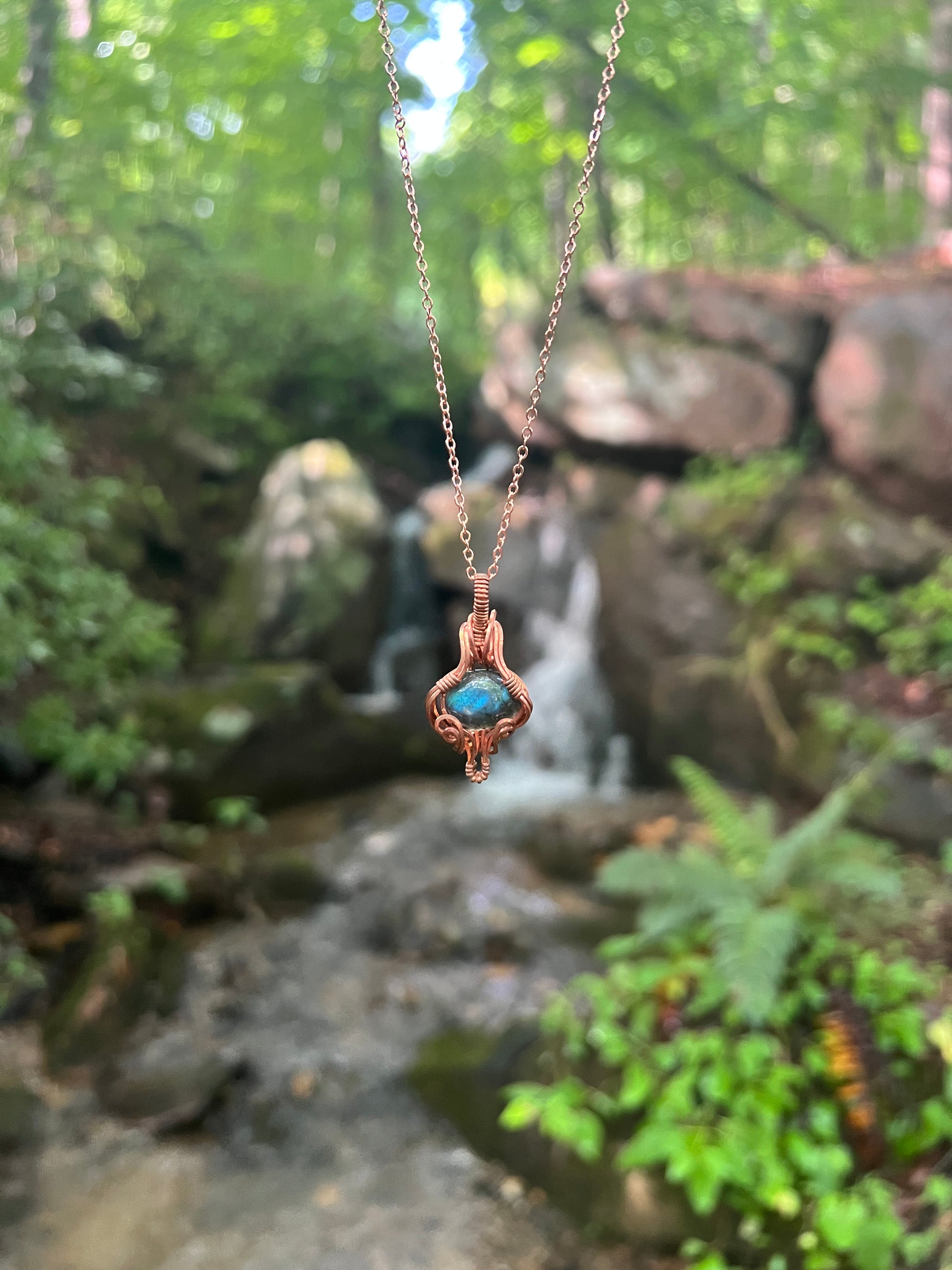 Labradorite pendant in front of a waterfall 