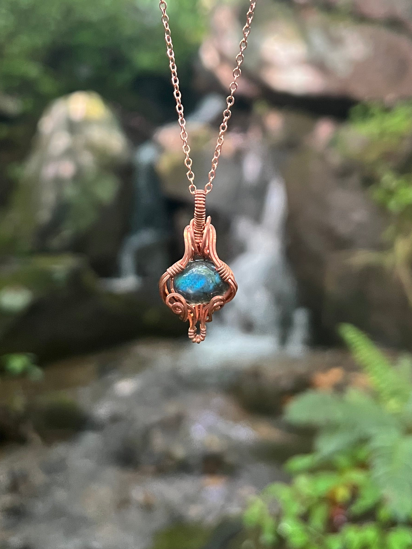 Copper necklace with a labradorite stone pendant against a natural background