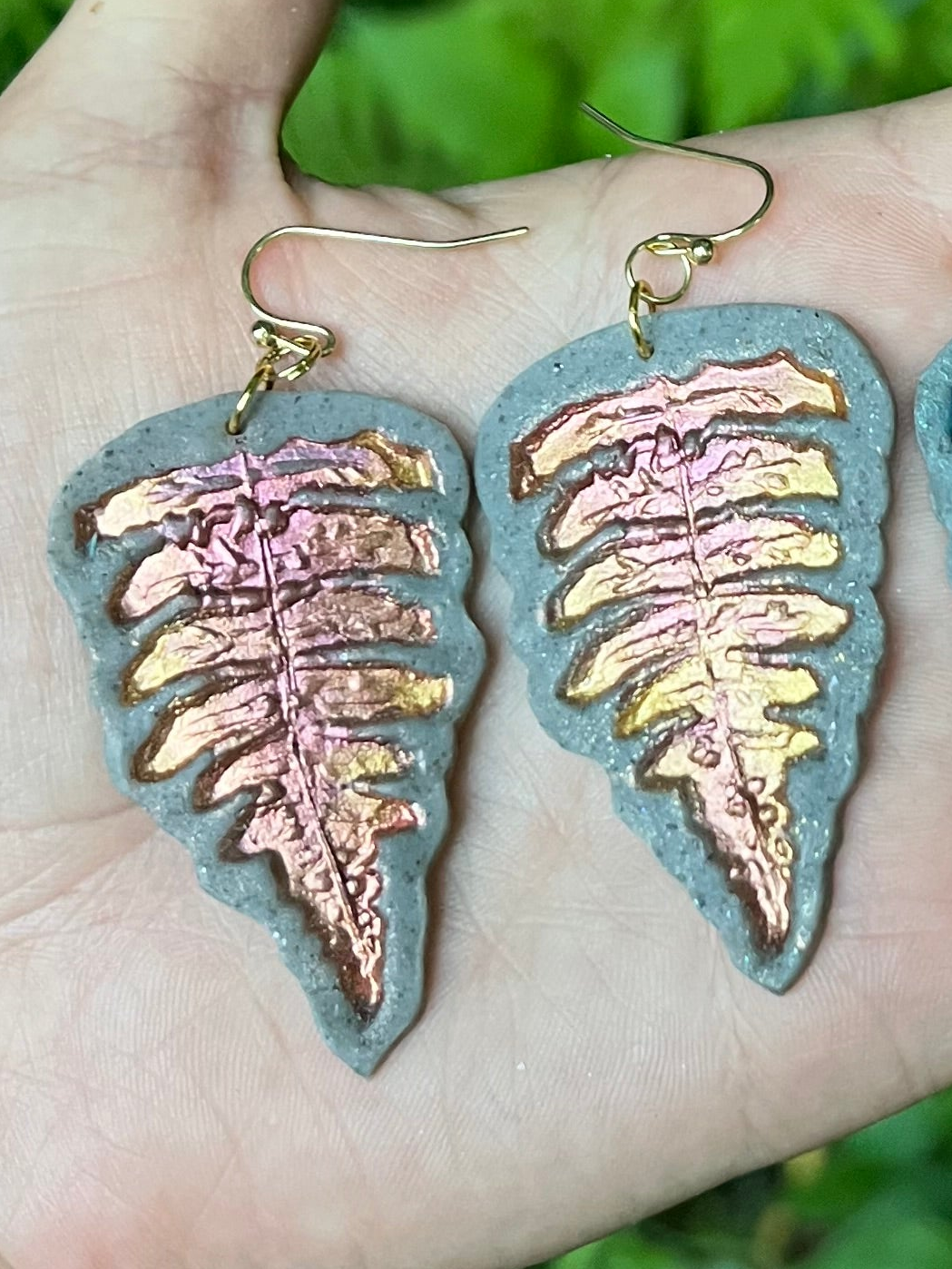 Hand holding polymer clay fern earrings 