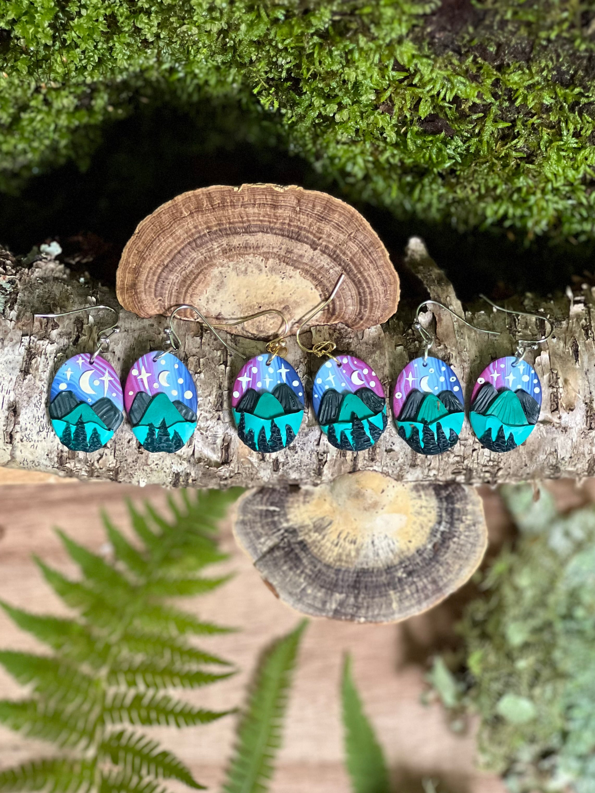 Hand-sculpted starry blue ridge mountain polymer clay earrings on natural surface. 