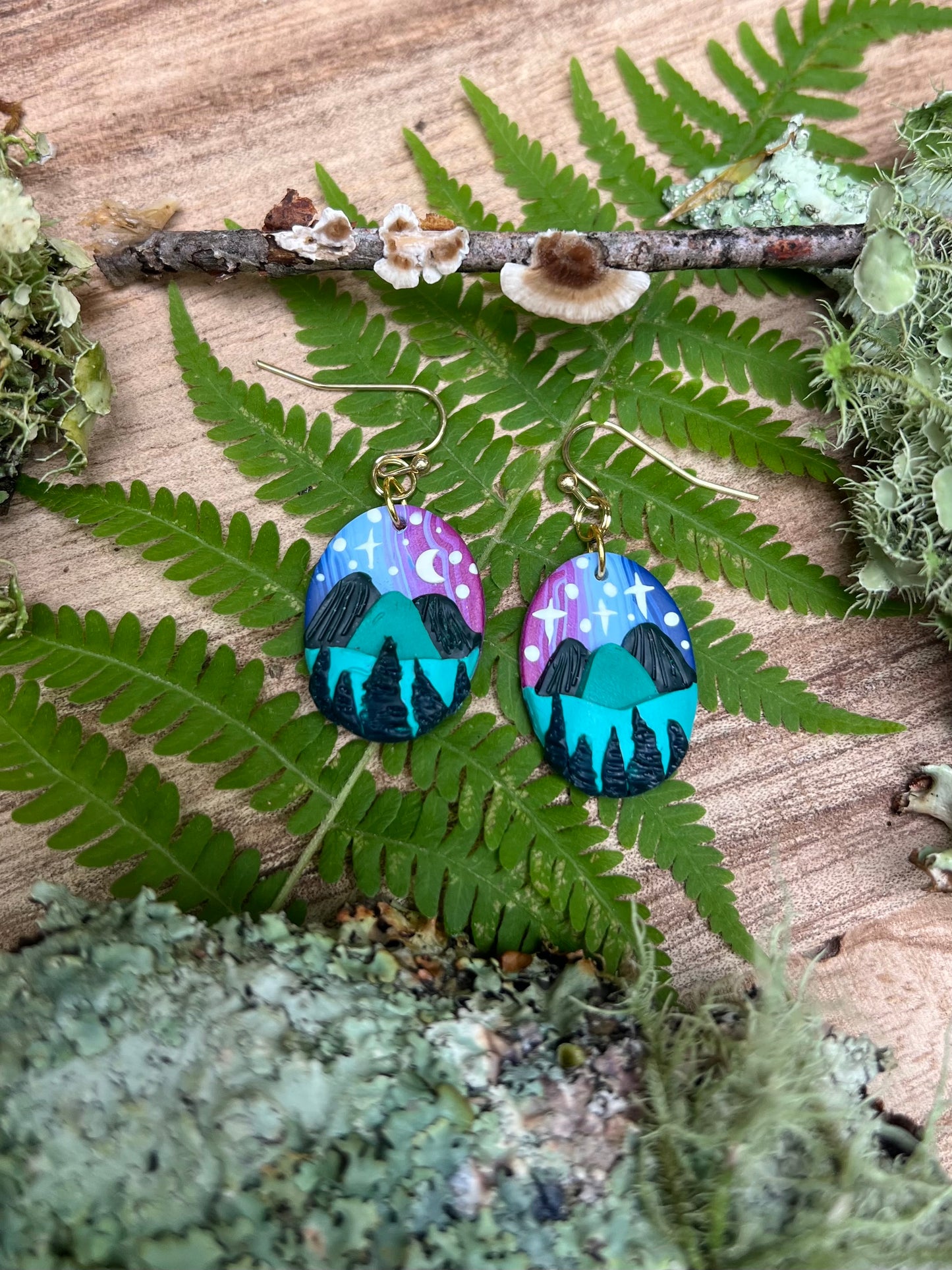 Hand-sculpted starry blue ridge mountain polymer clay earrings on natural surface. 