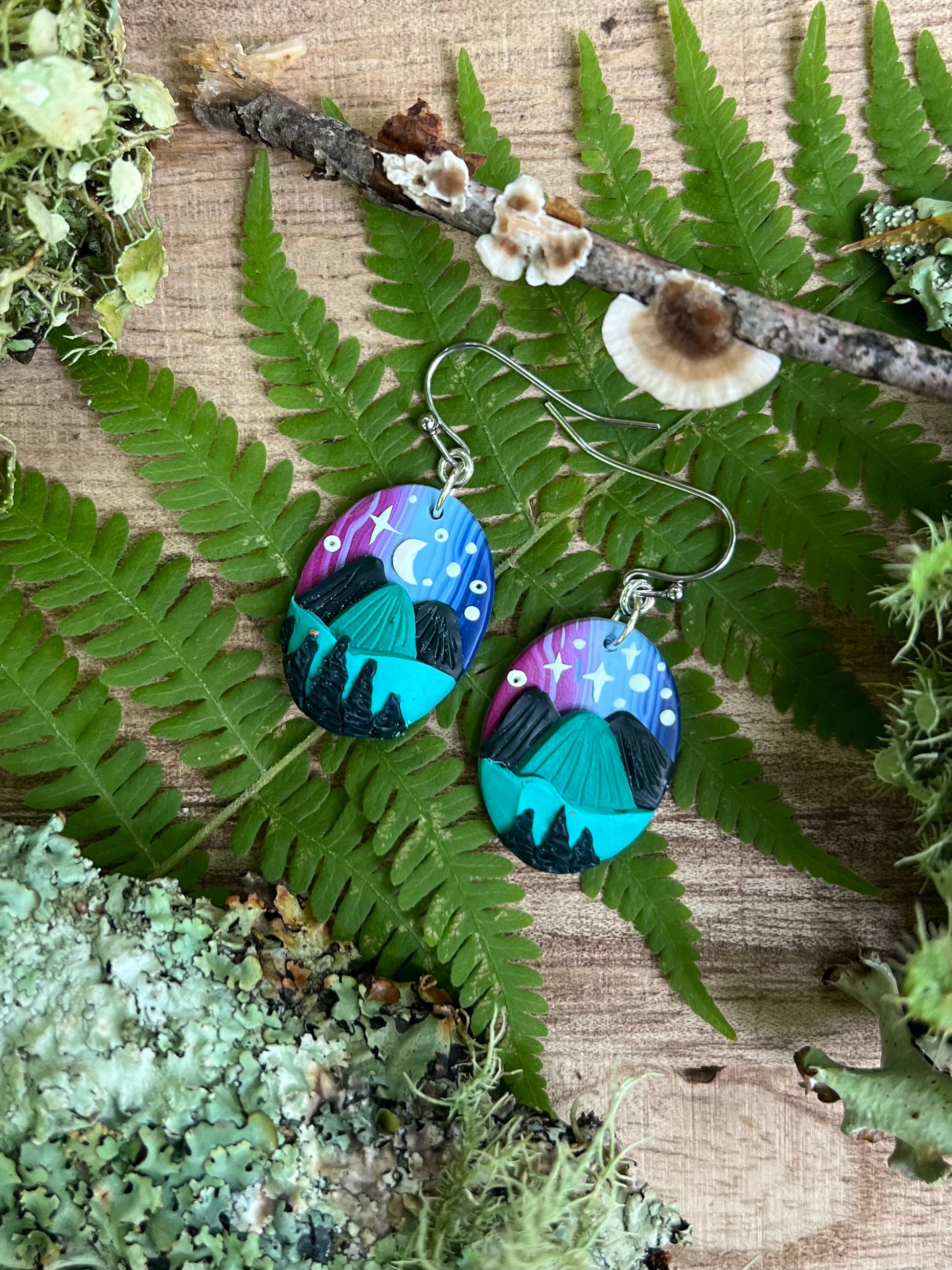 Hand-sculpted starry blue ridge mountain polymer clay earrings on natural surface. 