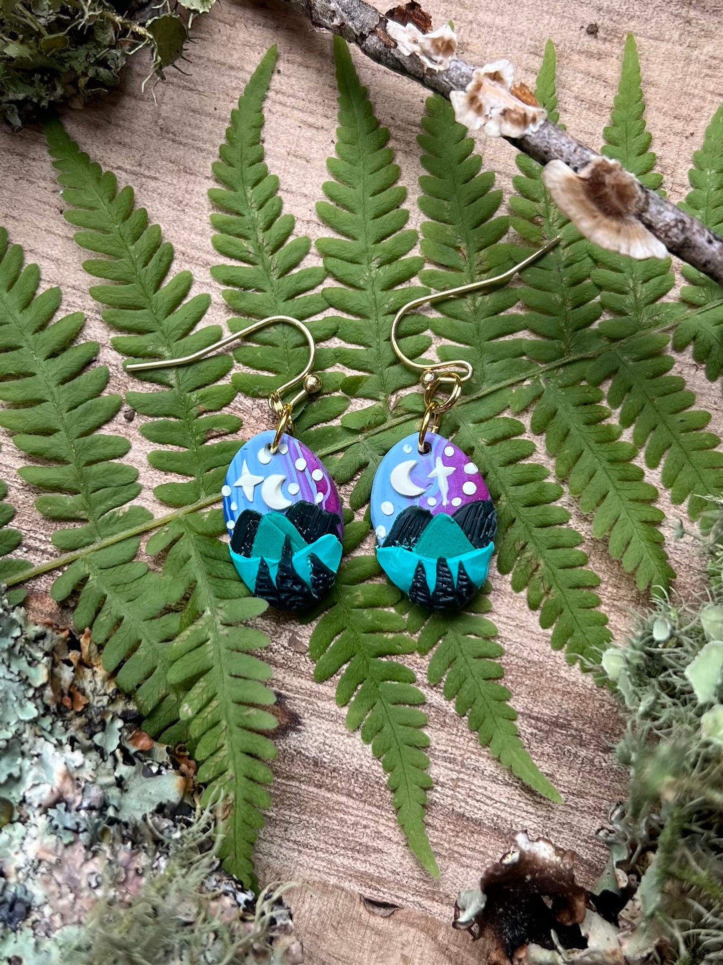 Hand-sculpted starry blue ridge mountain polymer clay earrings on natural surface. 