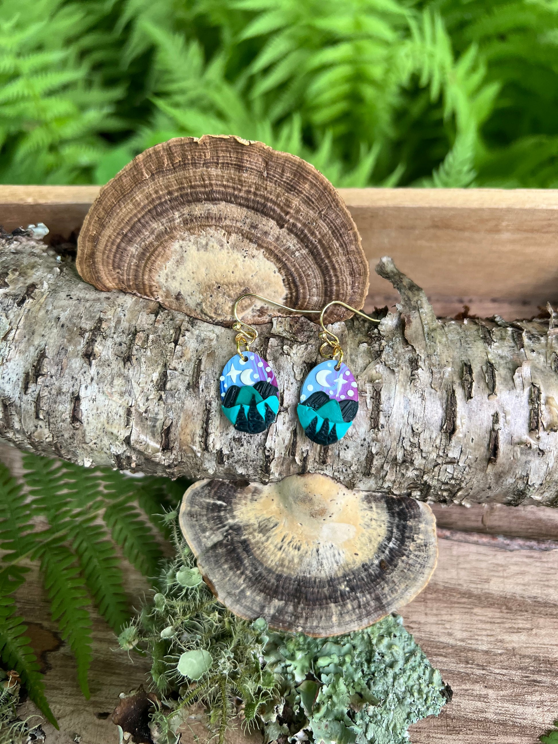 Hand-sculpted starry blue ridge mountain polymer clay earrings on natural surface. 