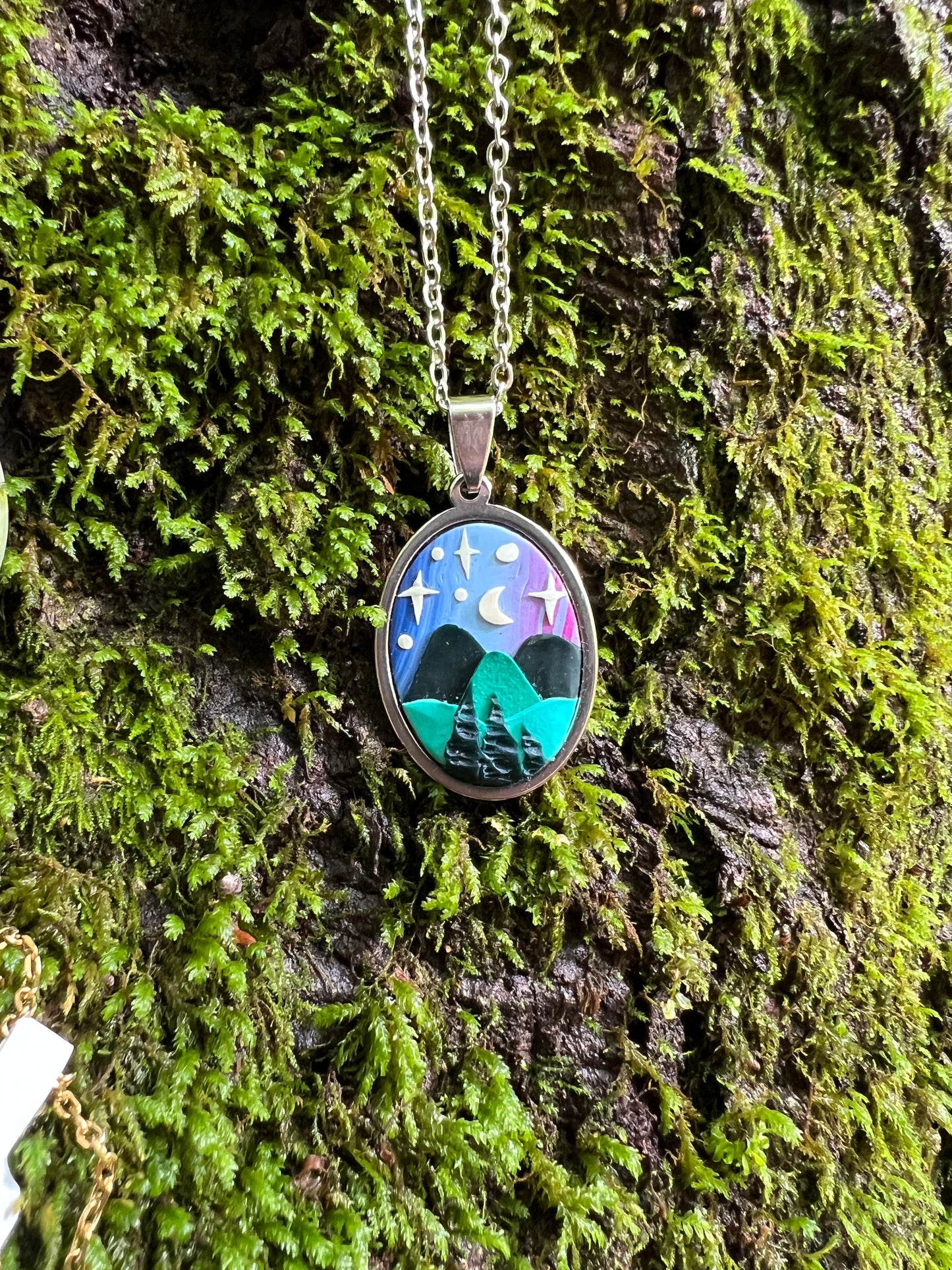 Necklace with a pendant featuring a nature scene on a mossy tree trunk.