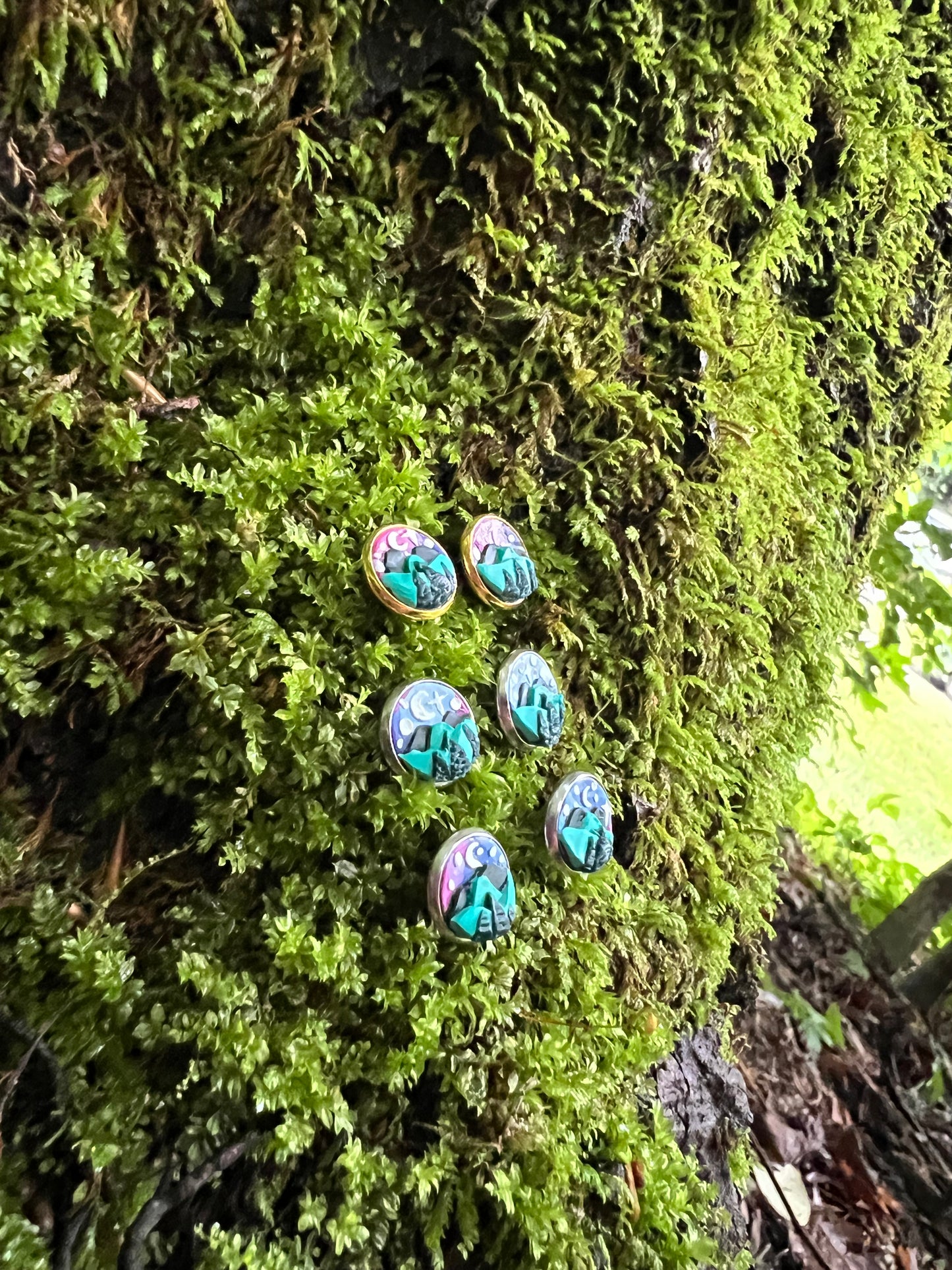 Starry mountain scene stud earrings on mossy stone background