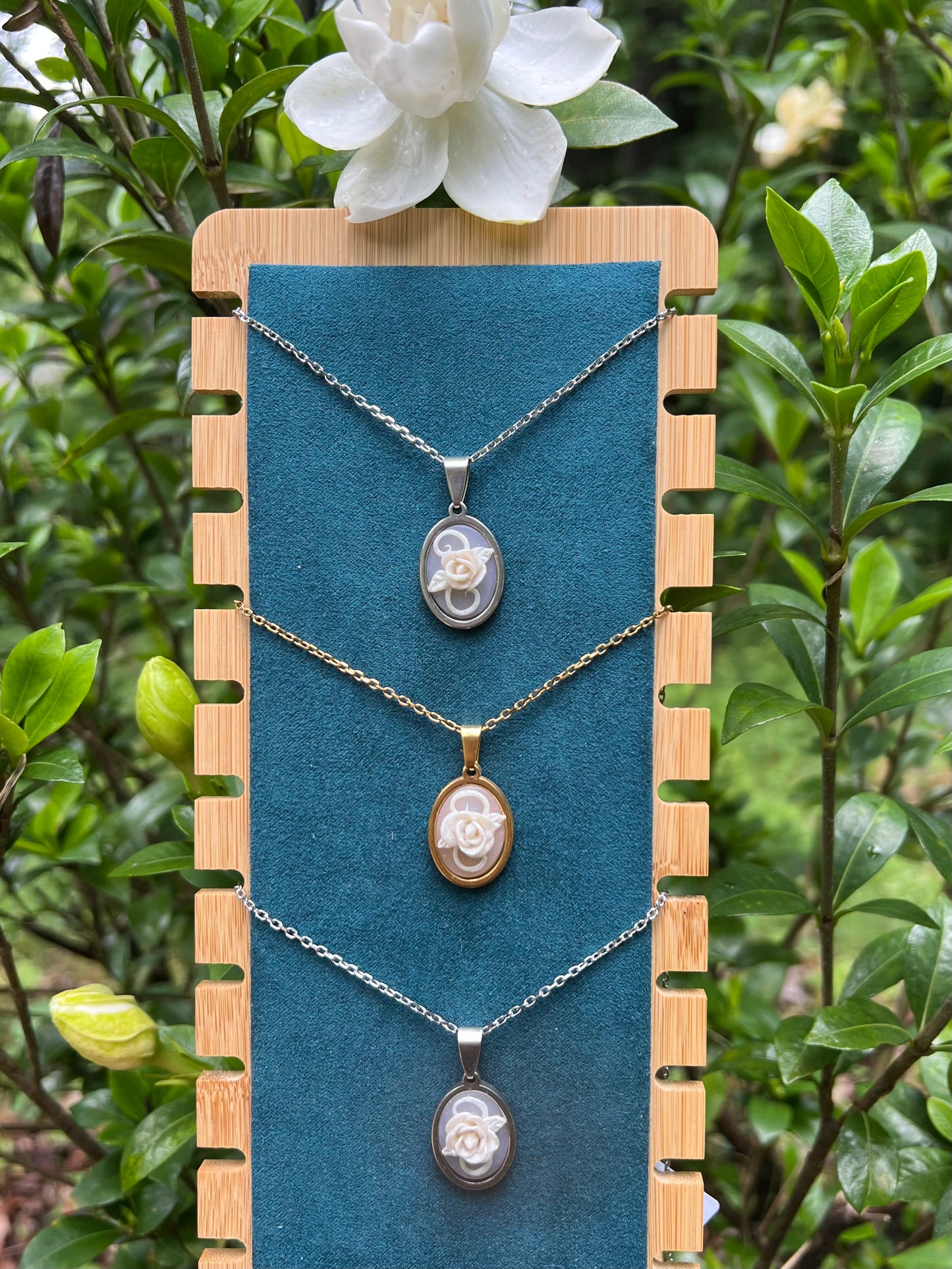 Hand sculpted white rose polymer clay necklaces with gardenias in the background 
