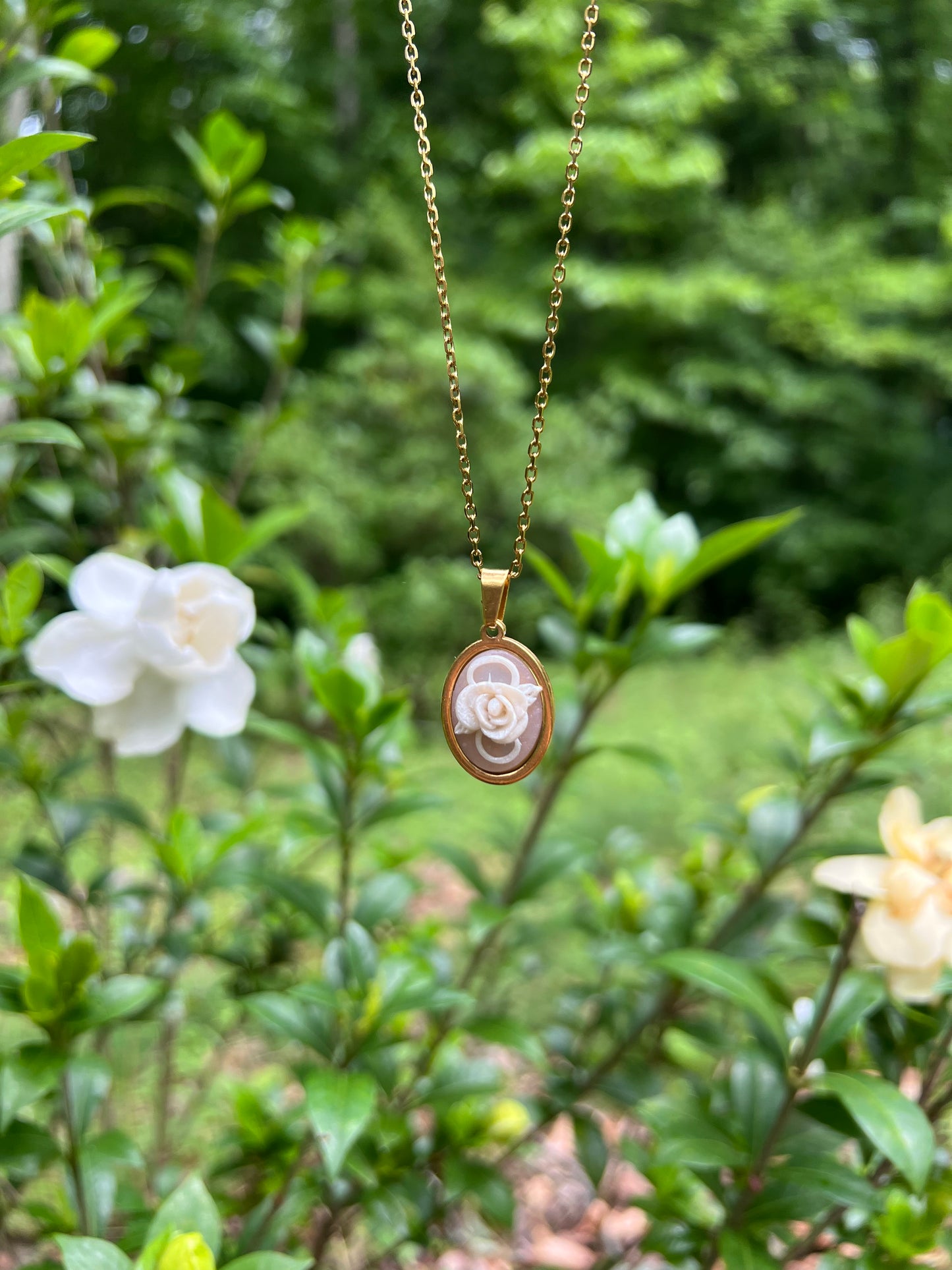 Rose Necklace with a floral pendant hanging among green leaves and white flowers