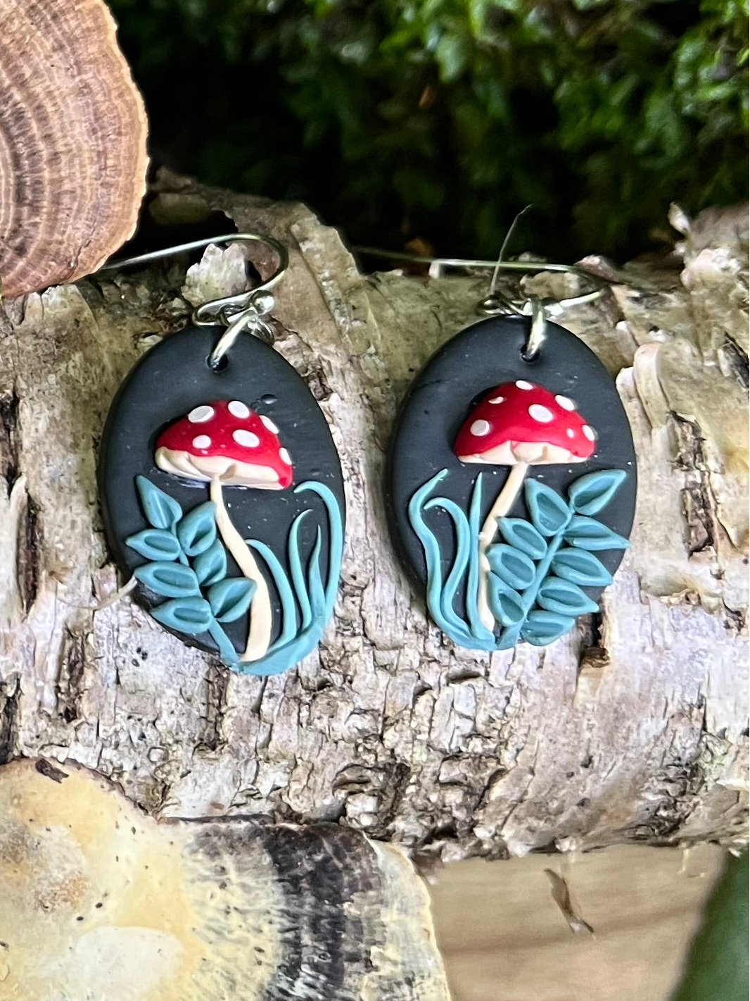 Mushroom-themed earrings on a wooden surface with a natural background