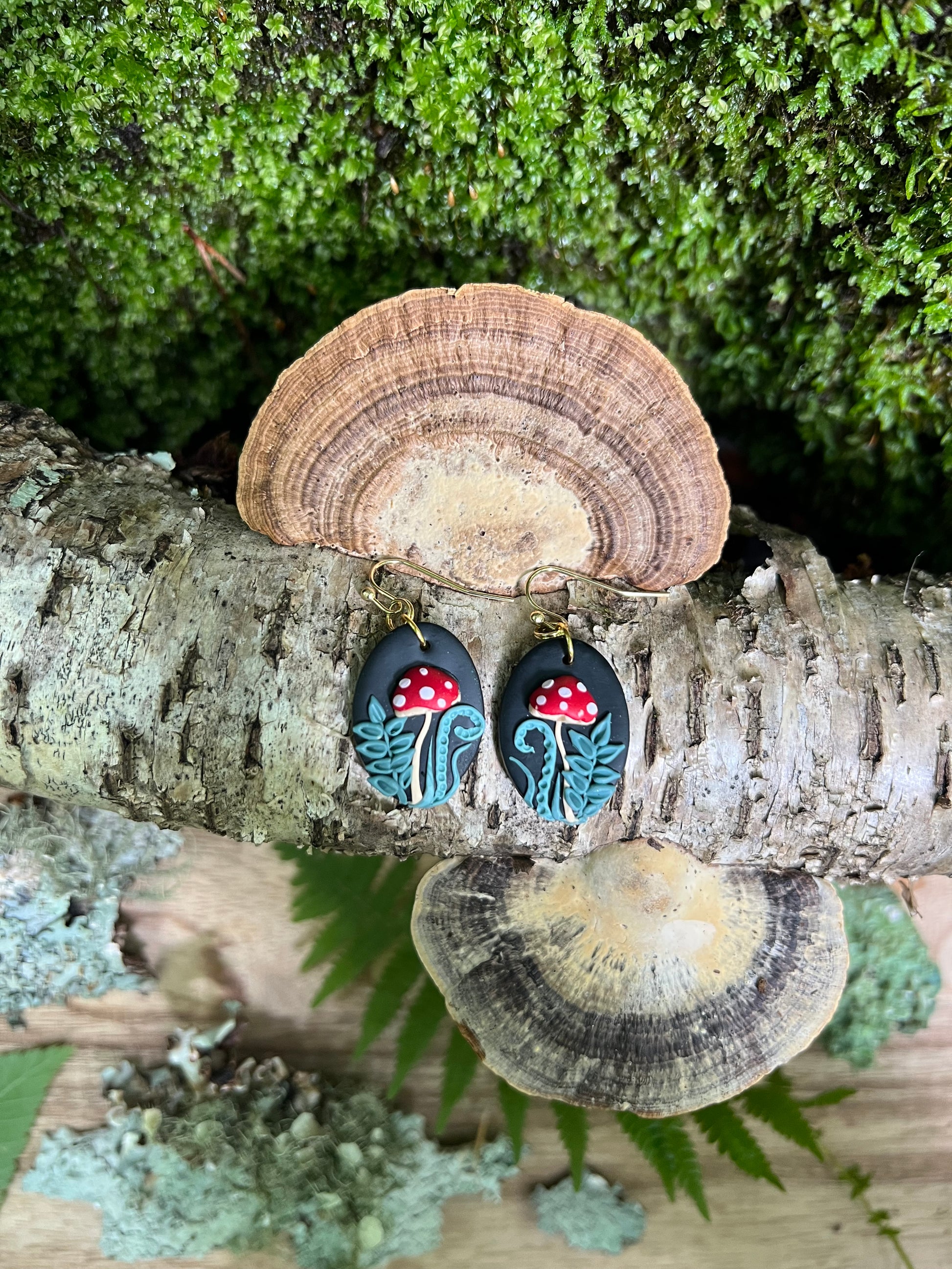Pair of earrings with red mushroom design on a tree bark background